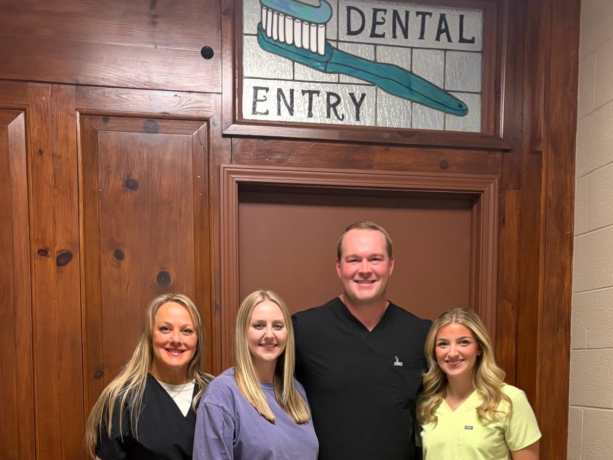 The Servolution Dental Family team standing beneath the Dental Entry sign